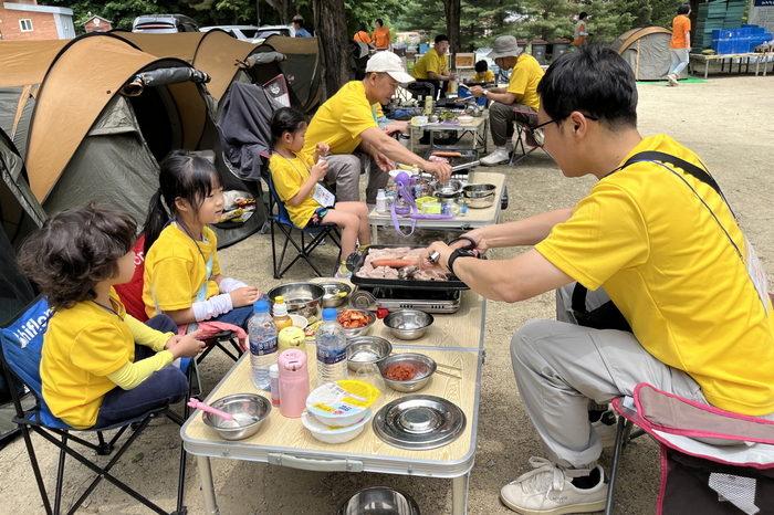 아빠가 아이들에게 고기를 구워주고 있다.