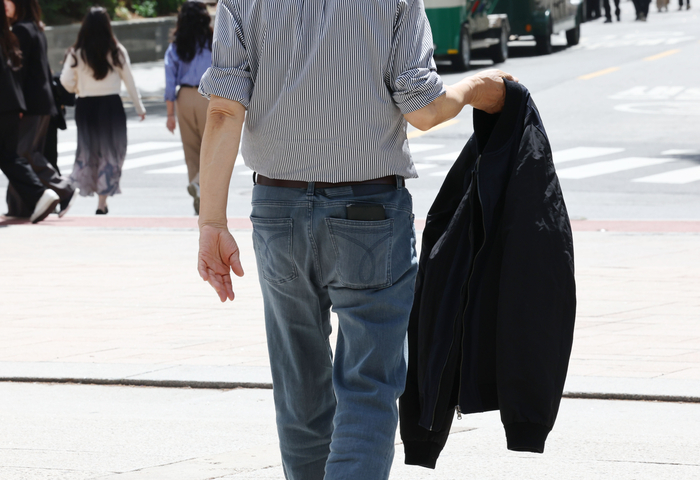 서울 청계천에서 한 시민이 외투를 벗어 손에 들고 걷고 있다.연합뉴스