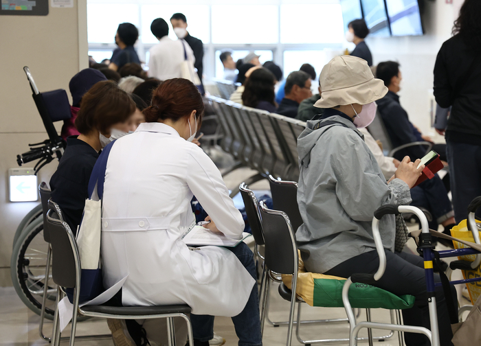 서울의 한 대학병원 진료실 앞에서 한 의사가 대기 중인 환자 진료를 보고 있다.연합뉴스
