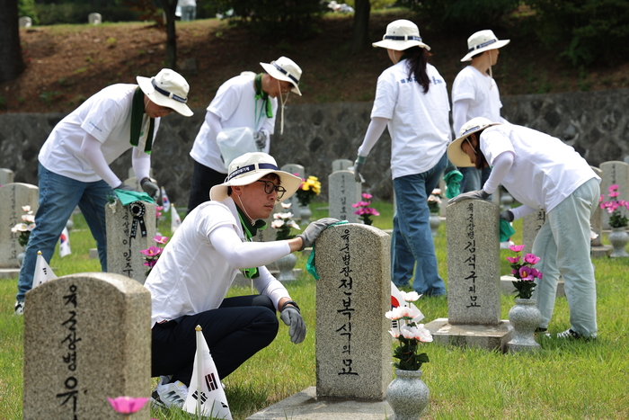 14일 서울 동작구 국립서울현충원 묘역에서 HD현대 임직원들이 묘역 정비 봉사 활동을 하고 있다.
