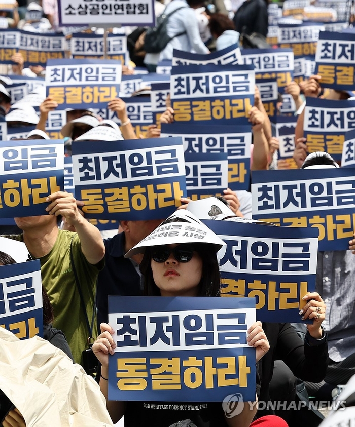 25일 오후 국회의사당역 인근에서 소상공인연합회 주최로 열린 최저임금 제도개선 촉구 결의대회에서 참석자들이 손피켓을 들고 있다.