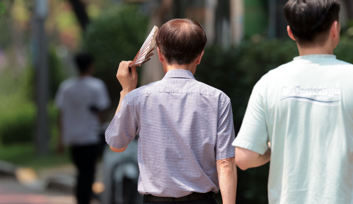 서울 영등포구 여의도공원에서 한 시민이 부채로 햇빛을 가리고 있다. 연합뉴스