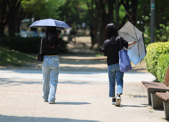 서울 성동구 서울숲에서 한 시민들이 양산을 꺼내 쓰고 있다.연합뉴스