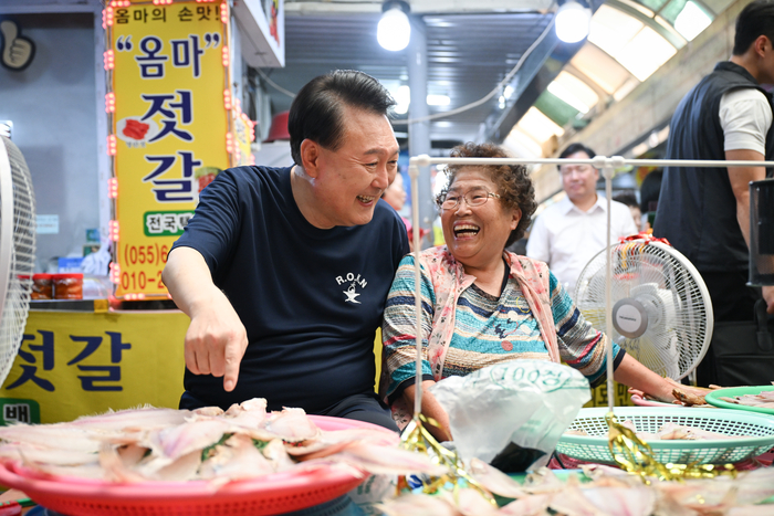 여름휴가 중인 윤석열 대통령이 지난 5일 경남 통영시 통영중앙시장을 찾아 상인들과 활짝 웃는 모습.대통령실/연합뉴스