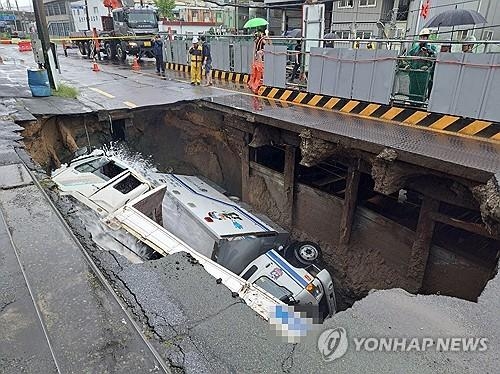 자료사진. 지난달 부산 사상구 한 도로에서 가로 10ｍ, 세로 5ｍ, 깊이 8m가량의 대형 싱크홀이 발생해 트럭 2대가 빠져있다.