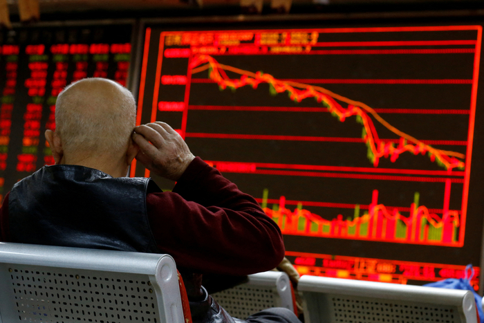 FILE PHOTO: An investor sits in front of a board showing stock information at a brokerage office in Beijing