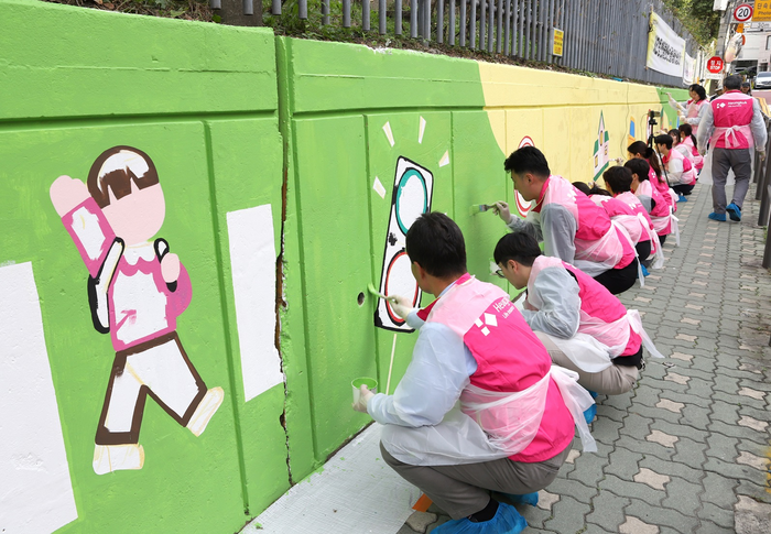 흥국생명 임직원들이 25일 서울 서초구 서일초등학교에서 스쿨존 벽화 그리기 봉사활동을 하고 있다.